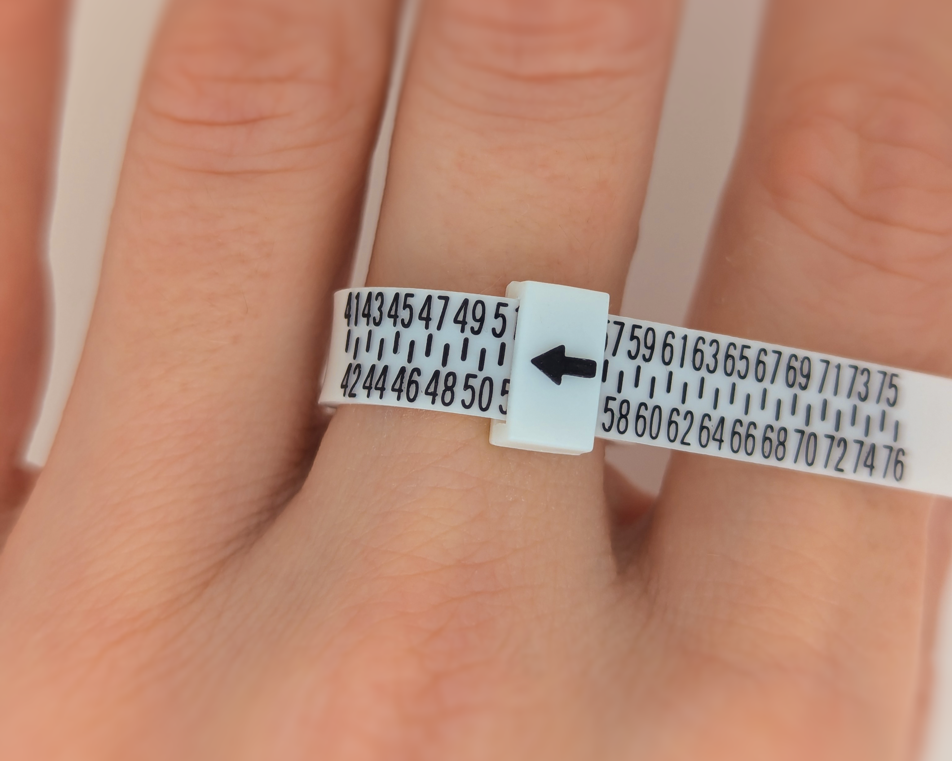 Ring size measuring tape used on a finger before ordering a HoloRing tungsten ring.