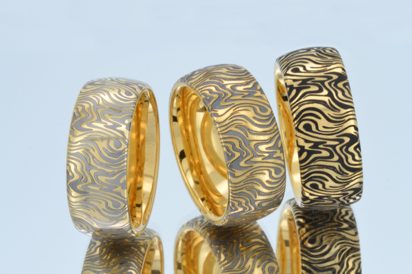 Three gold-tone HoloRing rings with abstract engraved patterns