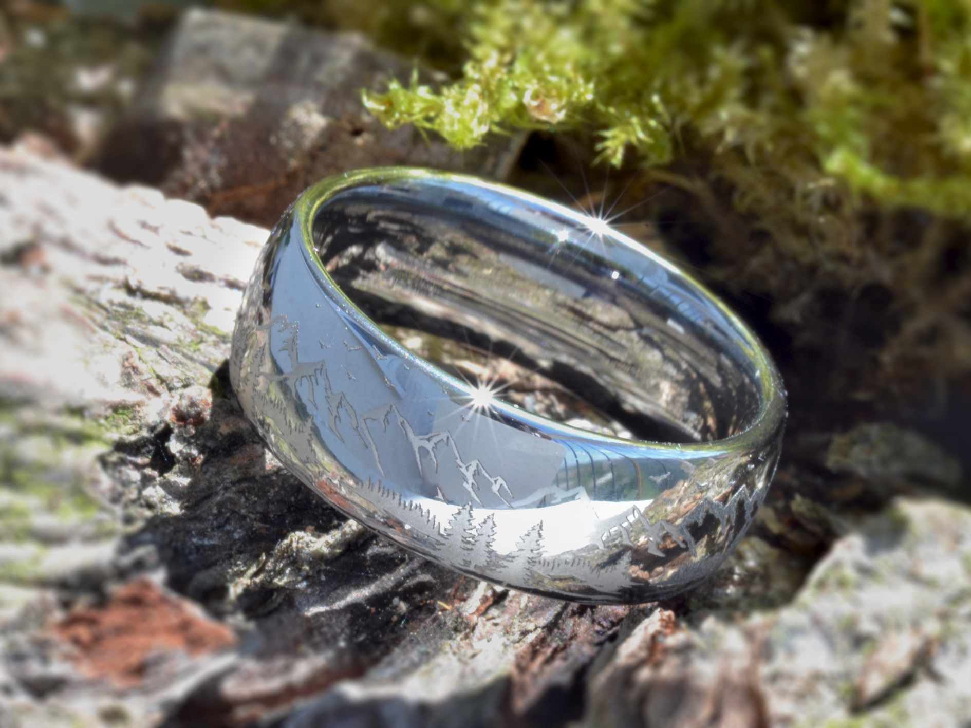 Silver tungsten ring with an engraved mountain range design, isolated on a white background.