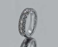 Silver ring with geometric pattern on a gray background