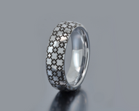 Silver ring with a patterned band on a gray background