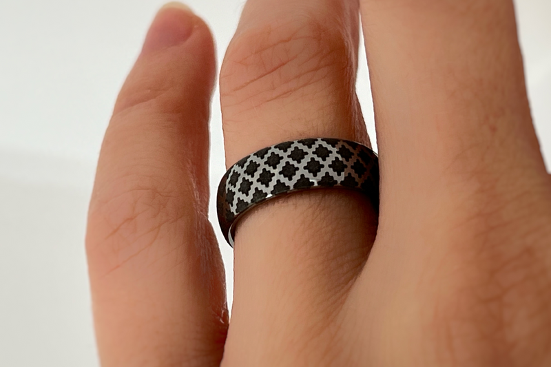 White gold tungsten ring with black engraved quilted pattern worn on hand