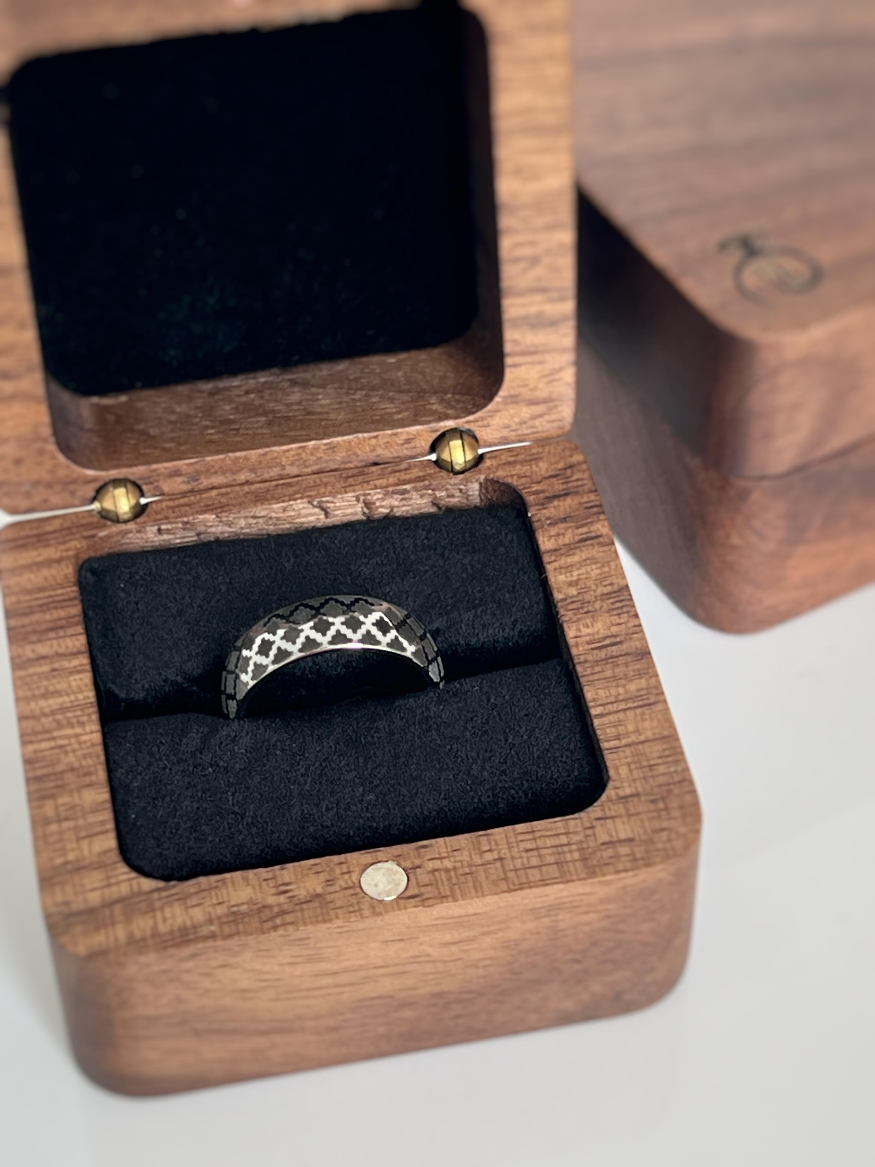 Tungsten ring with a white gold-plated surface and a timeless black diamond pattern engraving displayed inside wooden box