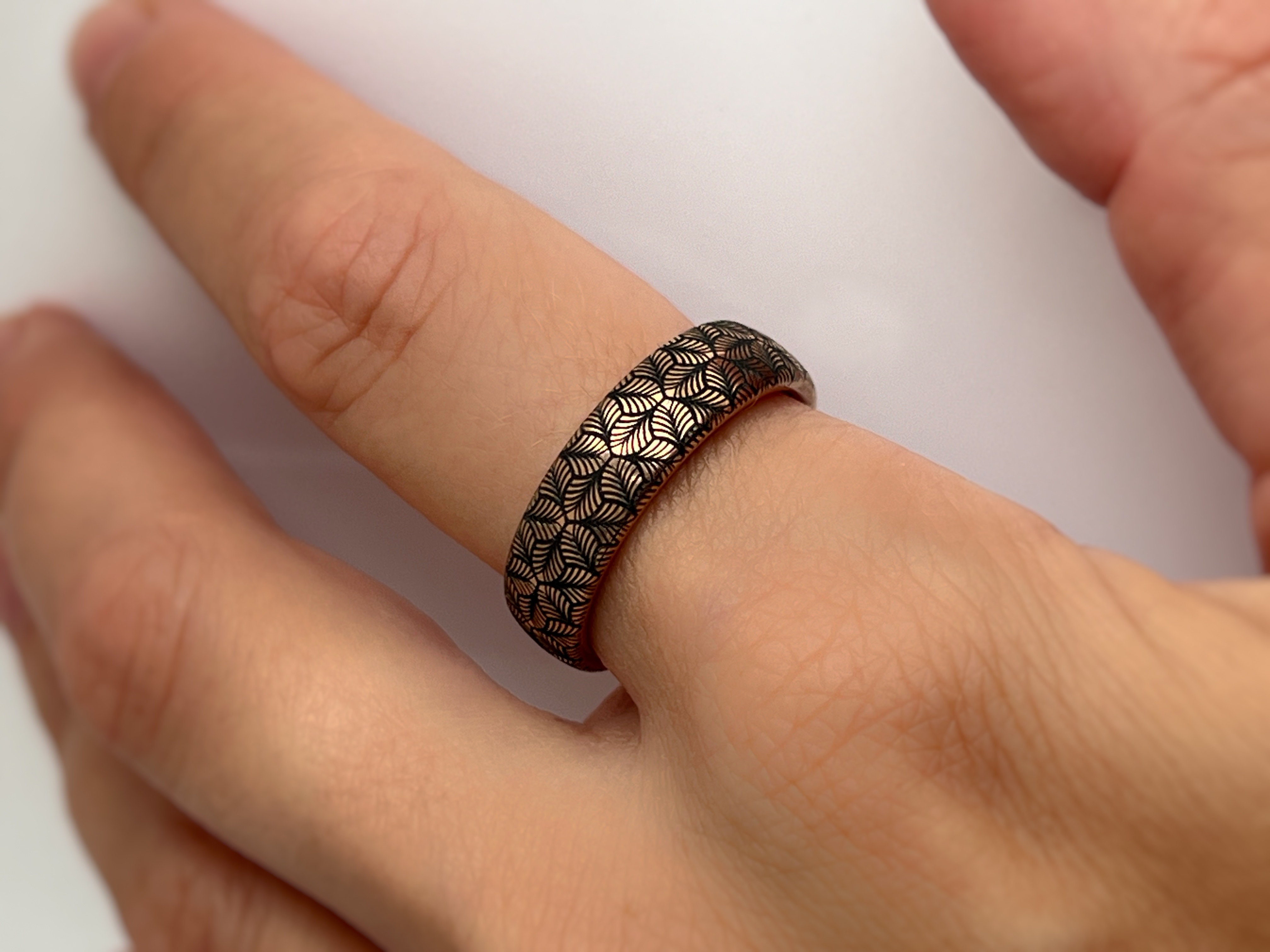 Rose gold tungsten ring with an intricate, black-engraved petal-like pattern,worn on hand offering a delicate and refined look, perfect for weddings, special occasions, or everyday wear.