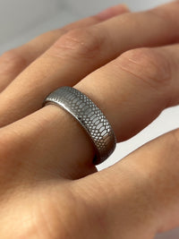 Product photo of the Serpente Eterno tungsten ring with laser-engraved surface detail.