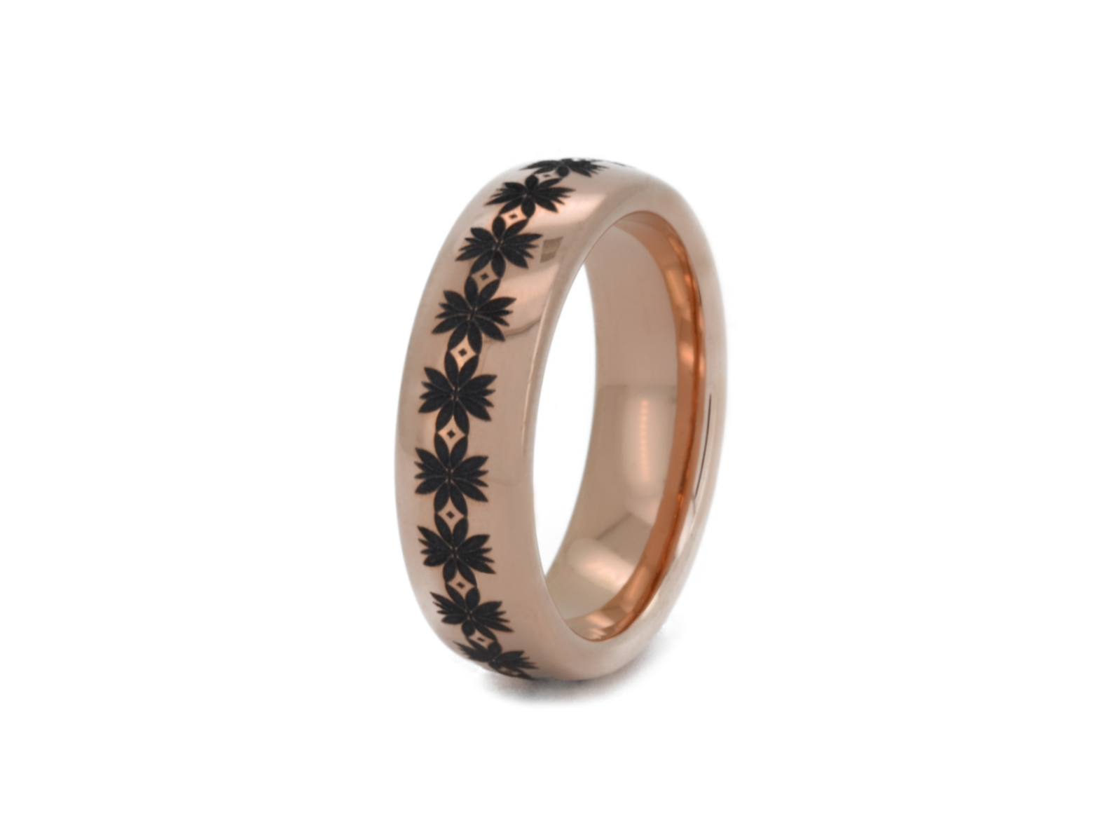 Rose gold ring with black floral engraving on a white background