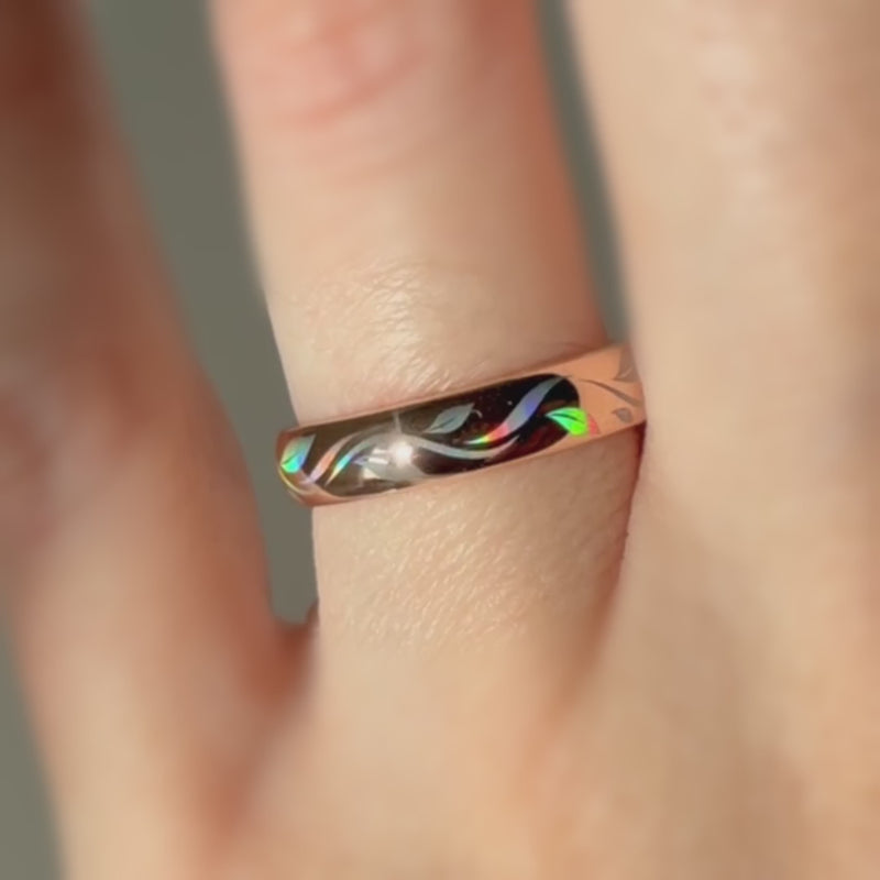 Video of a rose-gold Botanic Glow ring worn on a finger, with colorful organic lines shifting in the light.