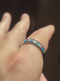 Baroque Radiance holographic tungsten ring worn on a finger in warm light.