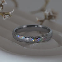 Close-up video of a silver holographic tungsten ring featuring an intricate rose and floral engraving with shimmering rainbow reflections. Elegant nature inspired wedding band with a polished finish.