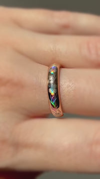 Video of a rose-gold Hibiscus Glow ring worn on a finger, with colorful hibiscus flowers and leaves shifting in the light.