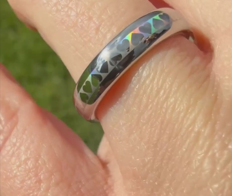 Close-up of a 4mm HoloHearts ring worn on hand, featuring holographic heart pattern on a polished silver band. Slim minimalist promise ring with romantic rainbow shine effect.