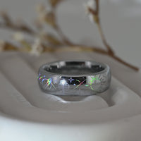 Video of a silver-tone Celestial Orbit ring on a pale display surface, showing holographic planets, stars and orbital lines.