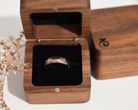 Rose gold engraved tungsten ring with oak leaf pattern displayed in a luxury wooden ring box with black velvet interior. Unique nature inspired wedding band gift.